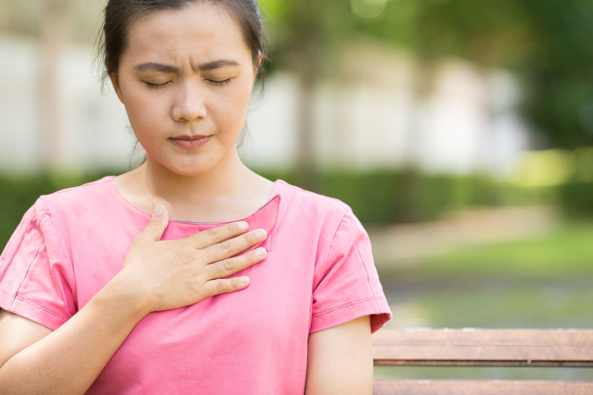 Woman has heartburn symptoms in the garden