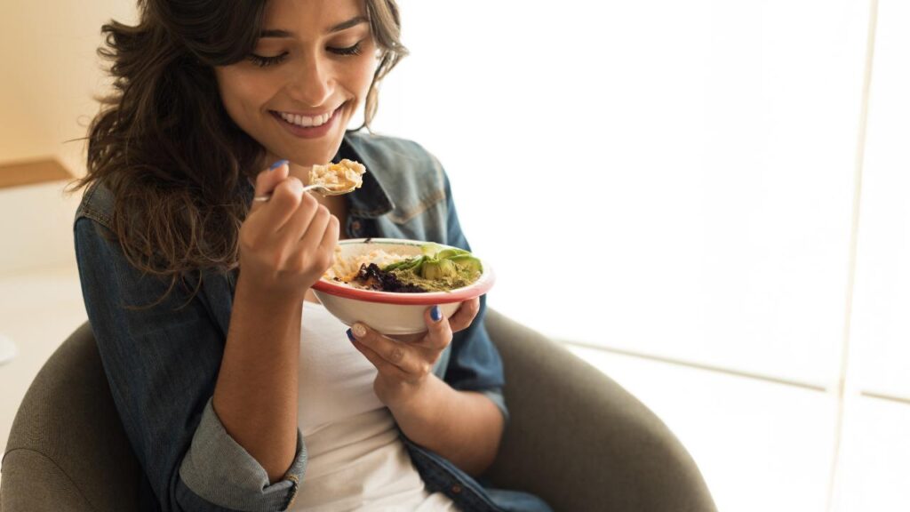 A woman about to take a bite from a healthy bowl of food that is showcasing a vegan diet. 
