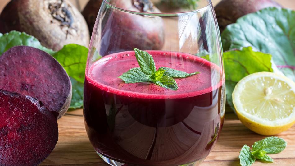 A close up of a beet juice mocktail to highlight the many uses and benefits of beet juice, along with other healthy and fresh ingredients in the background.